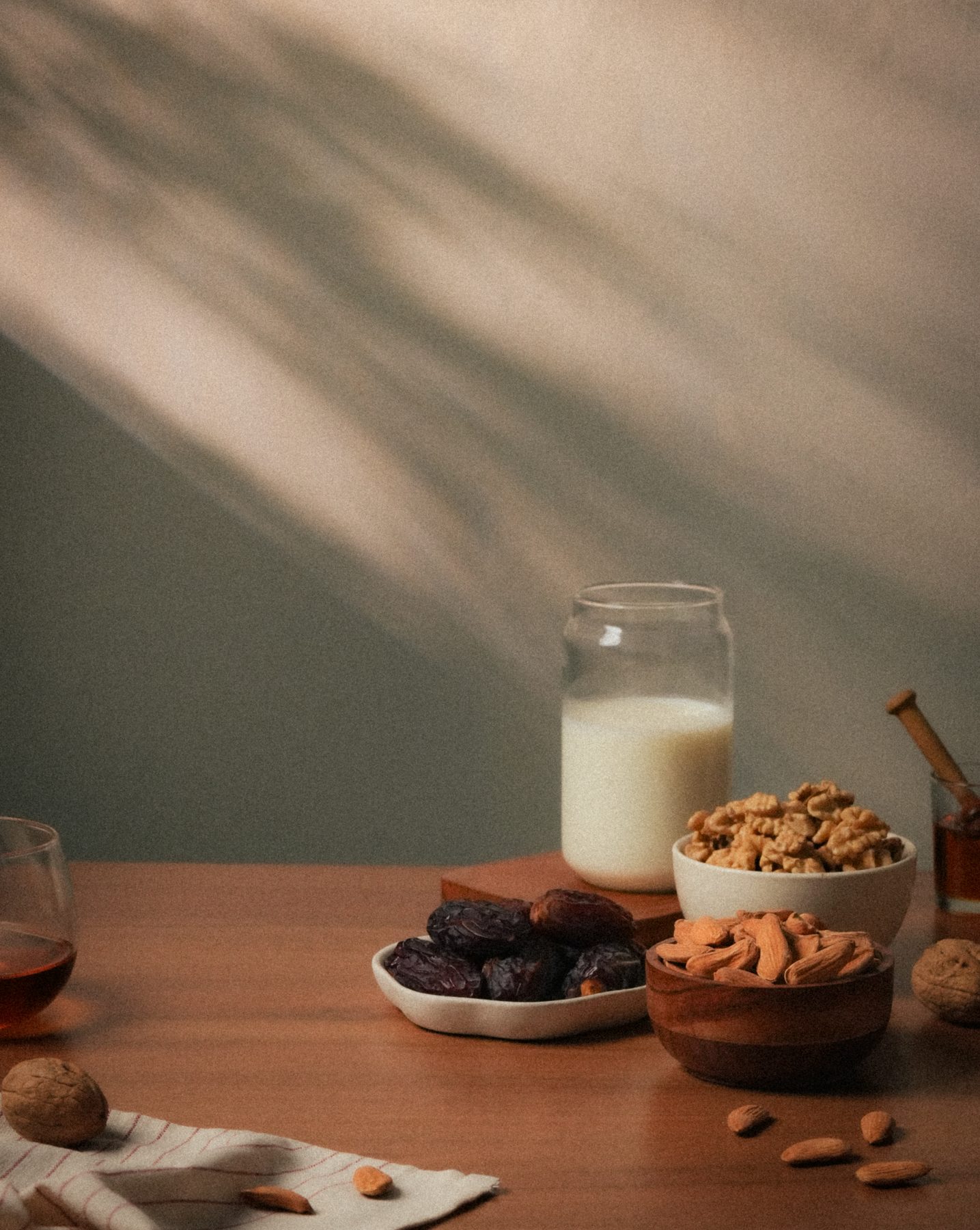 An editorial still life of dates, almonds, walnuts, milk, and honey — the quiet origin of remarkable things